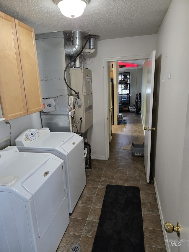 laundry area with a textured ceiling, independent washer and dryer, cabinet space, and baseboards