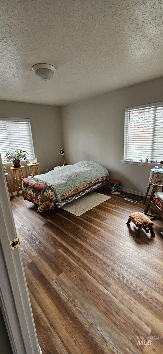 unfurnished bedroom featuring a textured ceiling, multiple windows, and wood finished floors