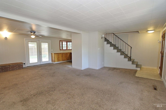 unfurnished living room with carpet floors, french doors, visible vents, and stairs