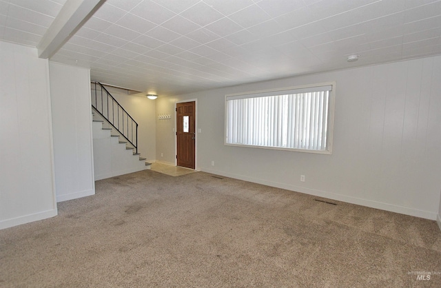 unfurnished living room featuring stairway, carpet, and baseboards