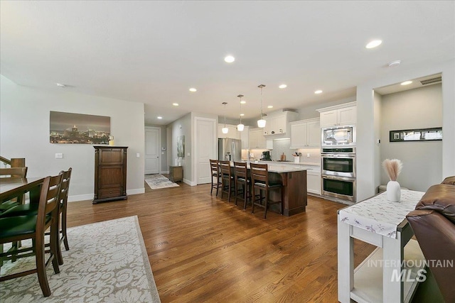 5726 N Morpheus Way, Meridian, ID 83642 - kitchen featuring stainless steel appliances, light countertops, a breakfast bar, dark wood-style floors, and recessed lighting