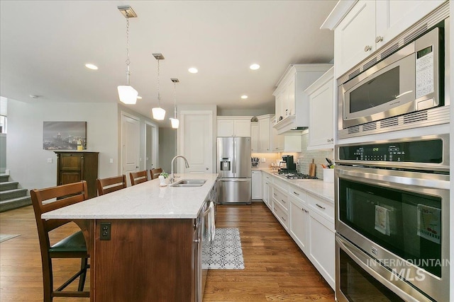 5726 N Morpheus Way, Meridian, ID 83642 - kitchen featuring appliances with stainless steel finishes, a sink, a kitchen bar, an island with sink, and white cabinets