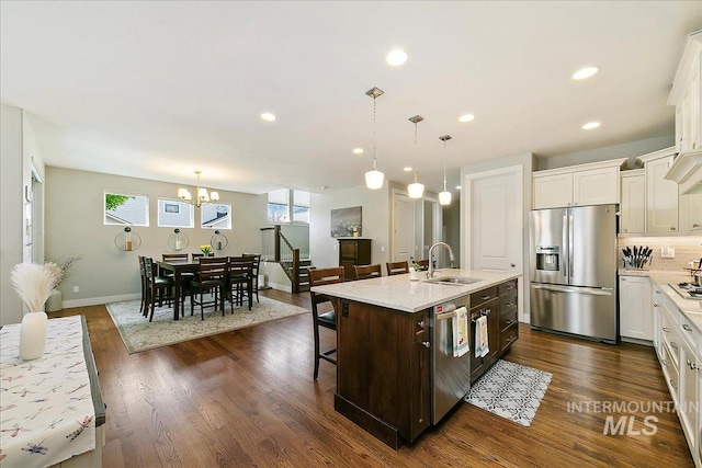 5726 N Morpheus Way, Meridian, ID 83642 - kitchen with appliances with stainless steel finishes, a sink, a chandelier, a kitchen breakfast bar, and white cabinets