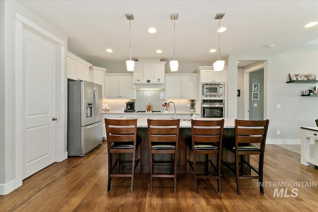 5726 N Morpheus Way, Meridian, ID 83642 - kitchen featuring appliances with stainless steel finishes, light countertops, decorative backsplash, white cabinetry, and dark wood-type flooring