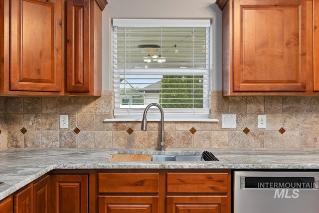 kitchen featuring light stone counters, tasteful backsplash, sink, and dishwasher