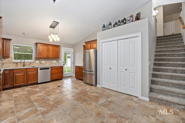 kitchen with lofted ceiling, tasteful backsplash, stainless steel appliances, sink, and decorative light fixtures