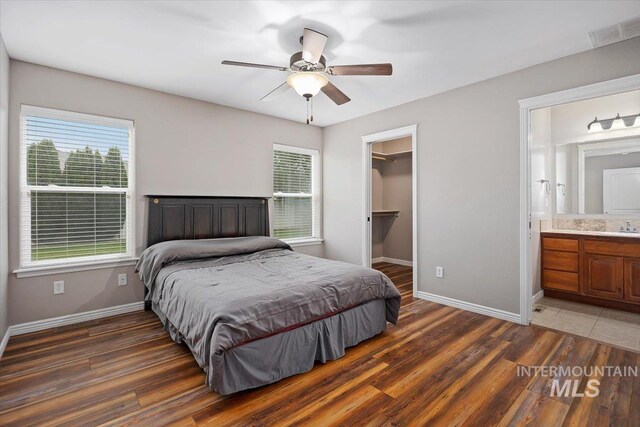 bedroom featuring a walk in closet, ceiling fan, dark hardwood / wood-style flooring, connected bathroom, and a closet