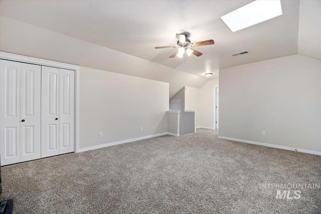 bonus room featuring vaulted ceiling with skylight, carpet flooring, and ceiling fan