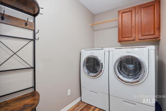 washroom with cabinets, wood-type flooring, and washing machine and dryer