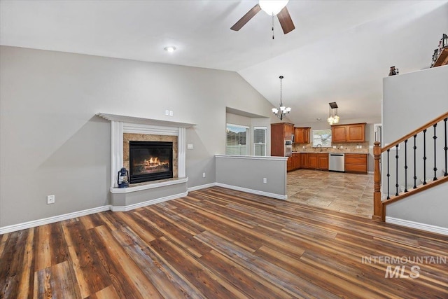 unfurnished living room featuring lofted ceiling, hardwood / wood-style flooring, sink, and ceiling fan with notable chandelier