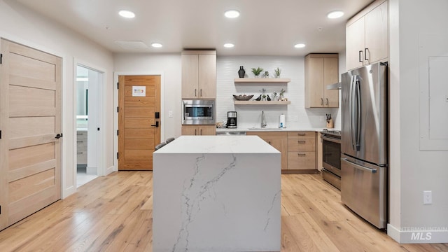 kitchen with light hardwood / wood-style floors, stainless steel appliances, sink, and a kitchen island