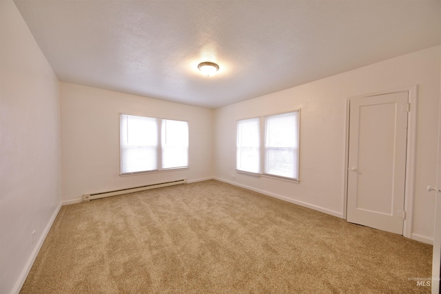 spare room with light carpet, a textured ceiling, and a baseboard heating unit