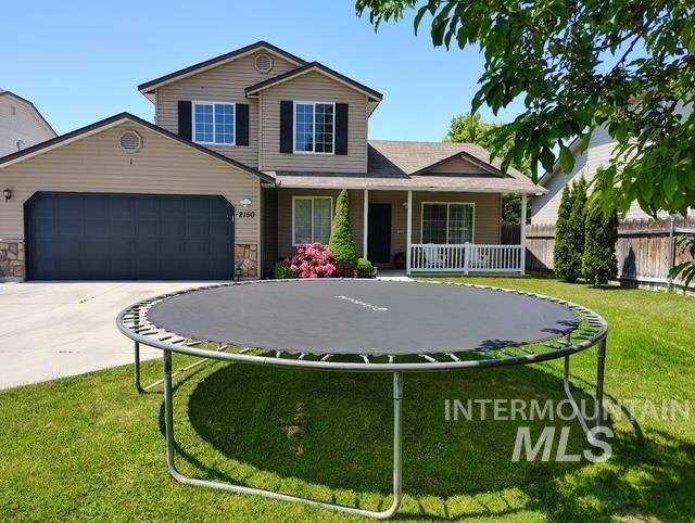 2150 W Shy Crk, Nampa, ID 83686 - view of front of house featuring a trampoline, an attached garage, covered porch, driveway, and stone siding