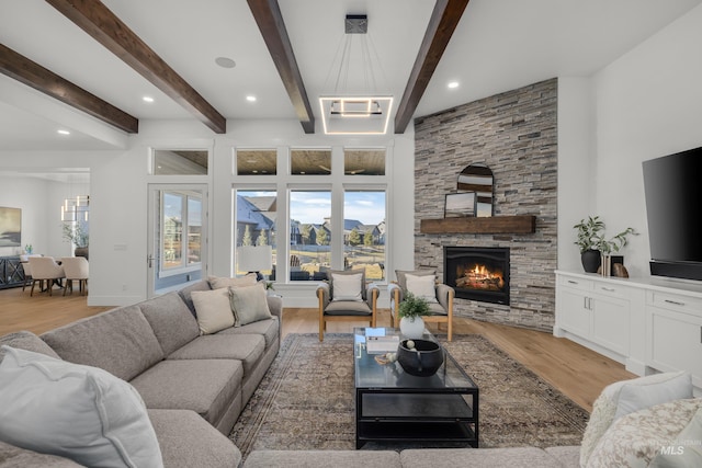 living area featuring light wood finished floors, a stone fireplace, beamed ceiling, and recessed lighting