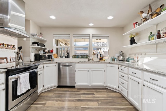 kitchen featuring hardwood / wood-style floors, appliances with stainless steel finishes, sink, white cabinetry, and exhaust hood