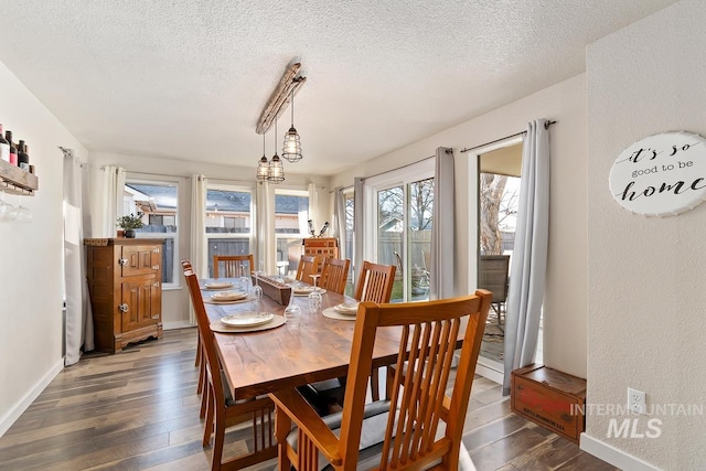 dining room featuring dark wood-type flooring, a textured ceiling, and an inviting chandelier