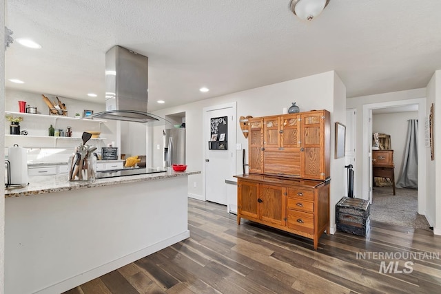 kitchen with island range hood, stainless steel fridge, dark hardwood / wood-style flooring, light stone counters, and a textured ceiling