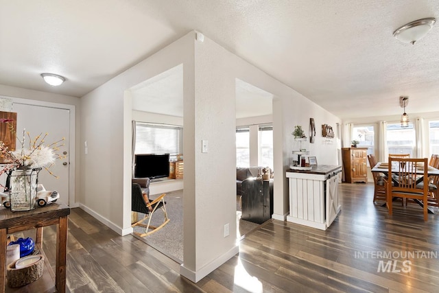 interior space with a healthy amount of sunlight, a textured ceiling, and dark hardwood / wood-style floors