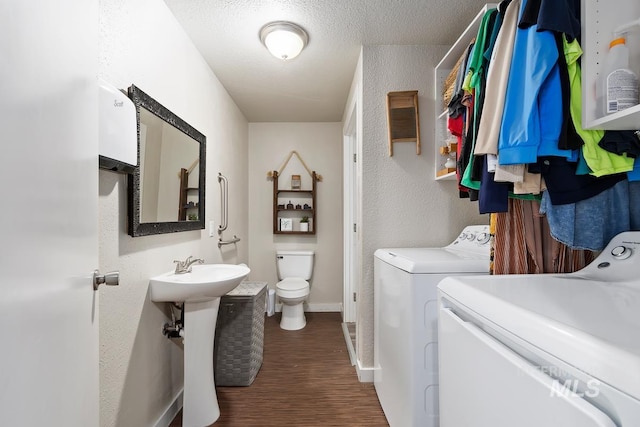 laundry area featuring a textured ceiling, dark wood-type flooring, and washing machine and dryer