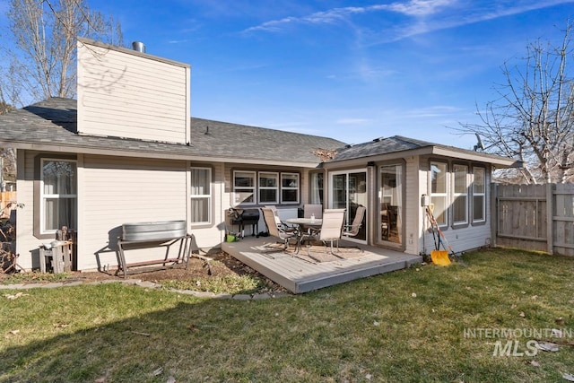 back of house with a wooden deck, a sunroom, and a lawn