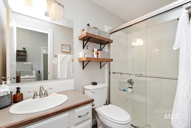 bathroom with vanity, backsplash, a shower with shower door, and toilet