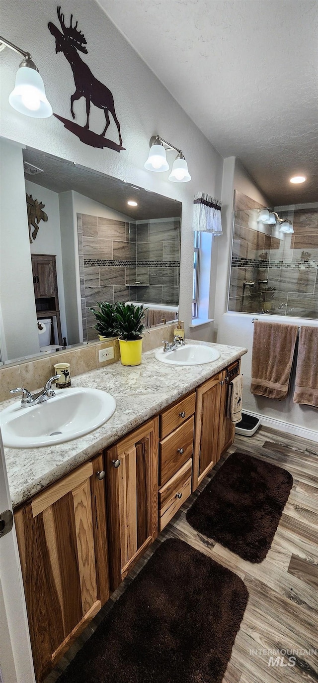 110 Memory Ln, Kamiah, ID 83536 - full bathroom with double vanity, a textured ceiling, tiled shower, and wood finished floors