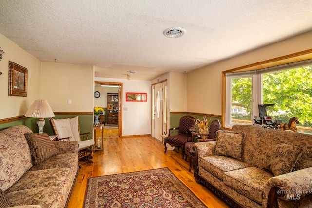 living room with light wood-type flooring and a textured ceiling