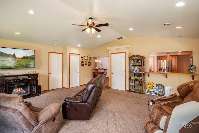 carpeted living room with ceiling fan and vaulted ceiling