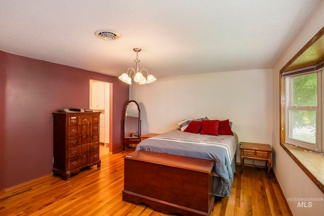 bedroom featuring a textured ceiling, a chandelier, and light hardwood / wood-style flooring