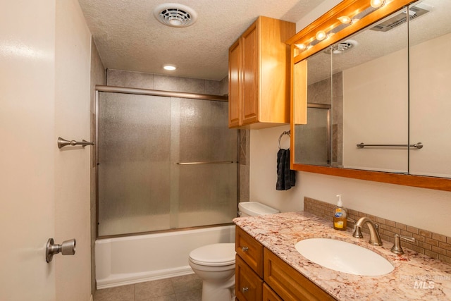 full bathroom featuring vanity, tile patterned flooring, toilet, shower / bath combination with glass door, and a textured ceiling