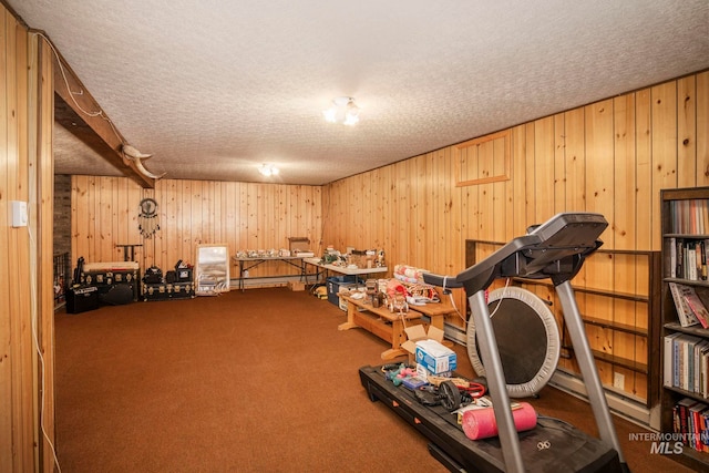 workout room featuring a textured ceiling, wood walls, and carpet flooring