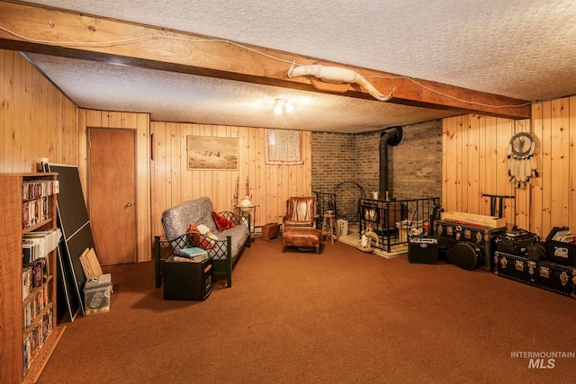 living area featuring a textured ceiling, wood walls, carpet flooring, and a wood stove