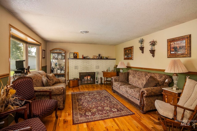 living room featuring a fireplace, wood-type flooring, and a textured ceiling