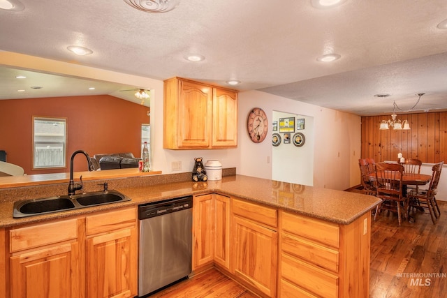 kitchen with light hardwood / wood-style floors, vaulted ceiling, wooden walls, dishwasher, and kitchen peninsula