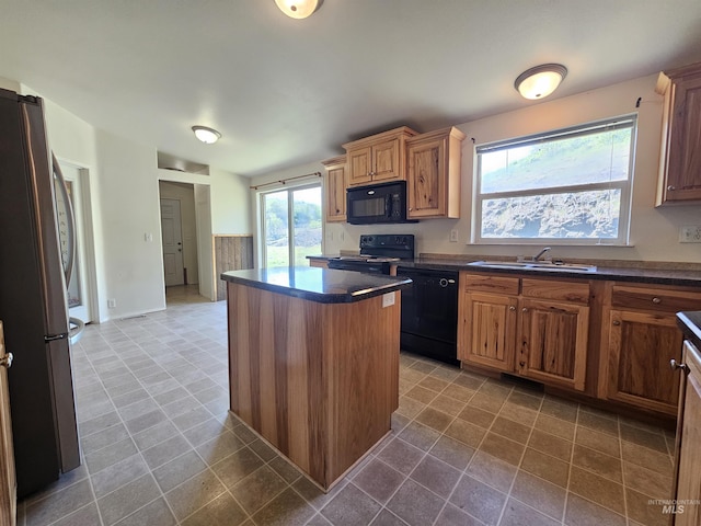 kitchen with black appliances, a sink, dark countertops, a center island, and healthy amount of natural light