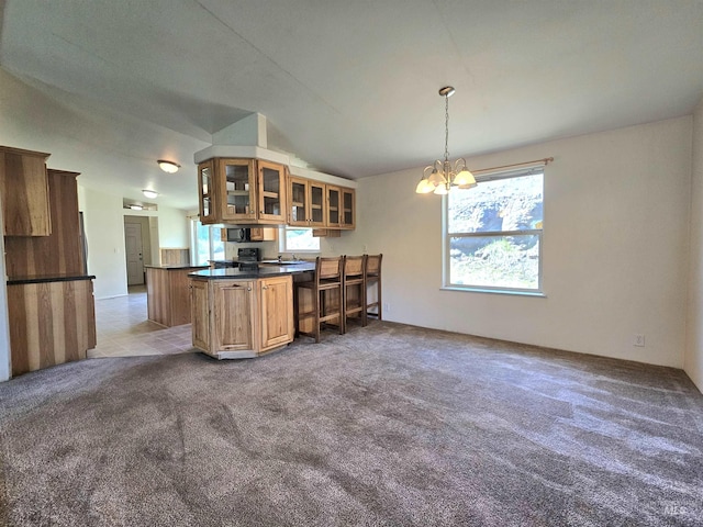kitchen featuring carpet, glass insert cabinets, a chandelier, dark countertops, and brown cabinets