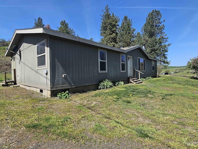 view of side of property featuring entry steps, crawl space, and a yard