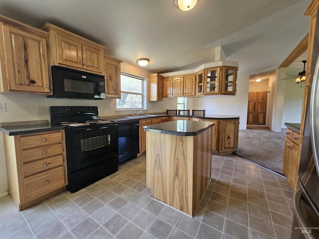 kitchen featuring black appliances, a center island, dark countertops, glass insert cabinets, and brown cabinets