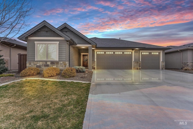 craftsman inspired home with a yard, stone siding, driveway, and an attached garage