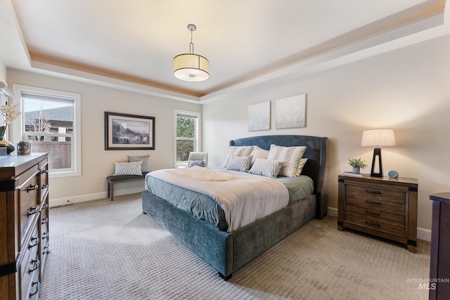 bedroom featuring a raised ceiling, multiple windows, and baseboards