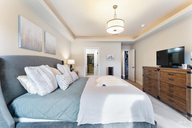 bedroom featuring visible vents, light colored carpet, a raised ceiling, and baseboards