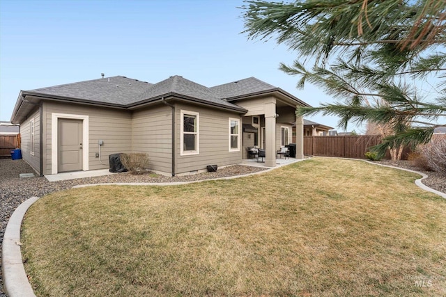 rear view of property with a patio area, a lawn, a shingled roof, and fence