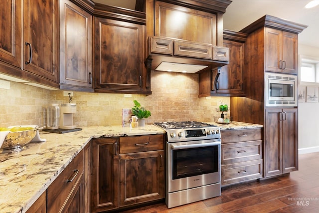 kitchen featuring light stone counters, dark wood finished floors, stainless steel appliances, and tasteful backsplash