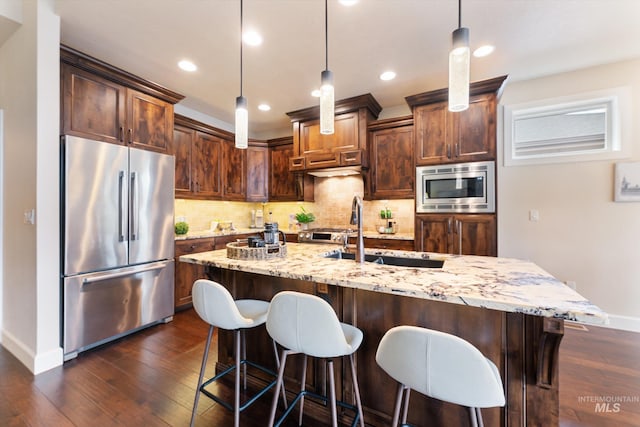 kitchen featuring tasteful backsplash, a sink, light stone countertops, appliances with stainless steel finishes, and dark wood-style flooring