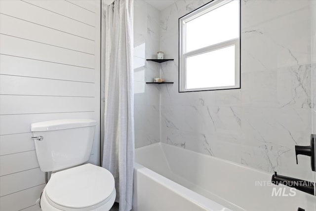 bathroom with toilet, shower / bath combo, and wood walls