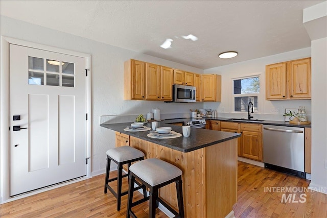 kitchen with appliances with stainless steel finishes, a kitchen bar, kitchen peninsula, and sink