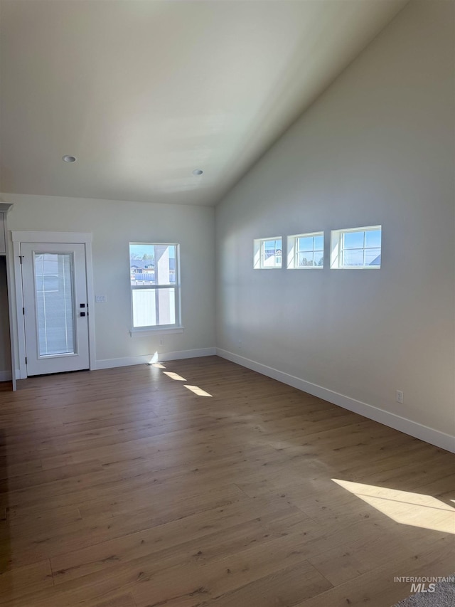 unfurnished living room featuring lofted ceiling, baseboards, and wood finished floors
