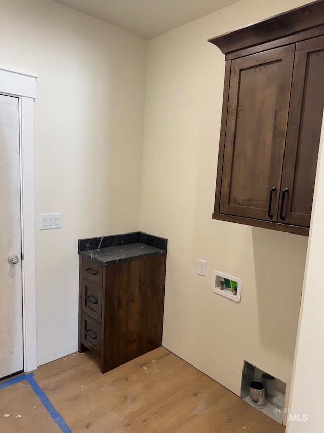 washroom with light wood finished floors, washer hookup, and cabinet space