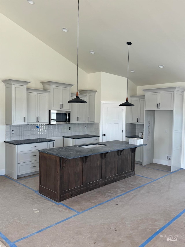 kitchen featuring backsplash, a large island, stainless steel microwave, and a breakfast bar area