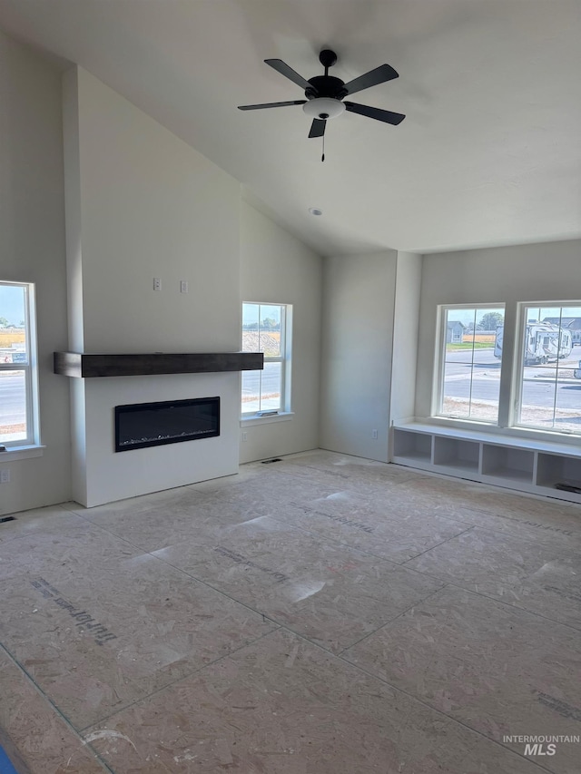 unfurnished living room featuring lofted ceiling, ceiling fan, and a wealth of natural light